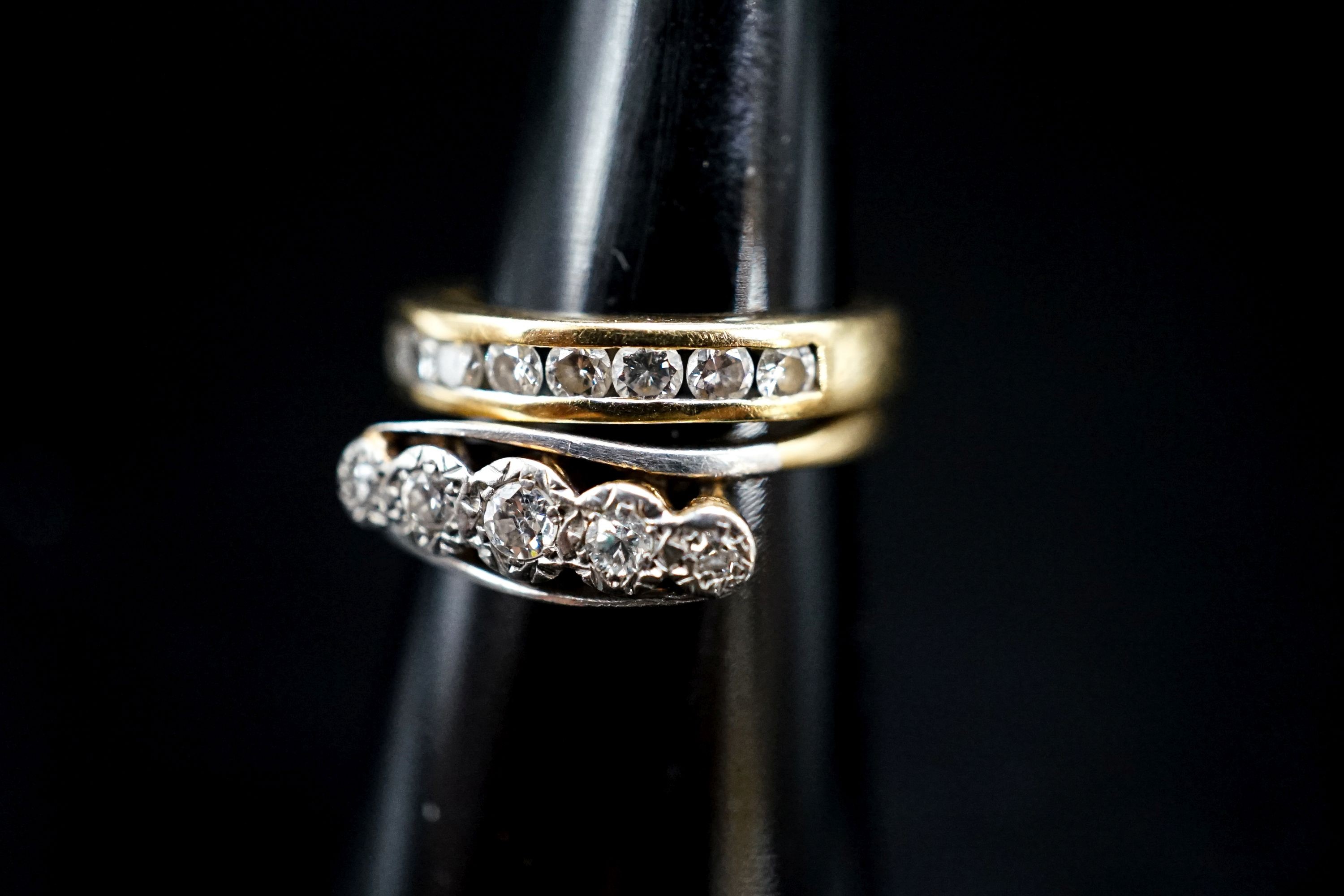 A 750 yellow metal and channel set nine stone diamond ring, size G, gross 2.6 grams and an early 20th century yellow metal and illusion set five stone diamond crossover ring, gross 2 grams.